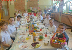 Uczniowie przy pięknie nakrytym i suto zastawionym stole podczas śniadanka wielkanocnego