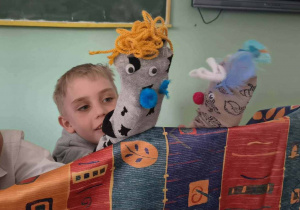 Dwaj chłopcy bawią się w teatr i grają rolę swoimi skarpetkowymi lalkami