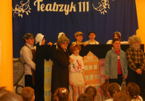 Scena z przedstawienia - na tle kamieniczek w kolorowej scenografii