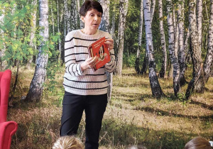 Pani bibliotekarka pokazuje dzieciom okładkę polecanej książki