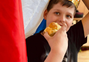 Uczeń w koronie na głowie z ciastkiem i flagą Francji w dłoniach