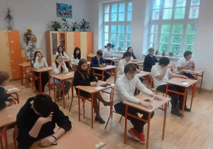 Uczniowie przy wylosowanych stolikach w sali egzaminacyjnej