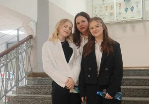 Trzy dziewczęta na stopniach schodów uśmiechają się do fotografii