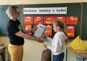 Uczennica przyjmuje dyplom i gratulacje od nauczycielki