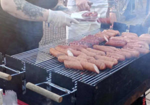 Rodzice doglądają grila, aż dym unosi się nad chrupiącymi kiełbaskami
