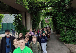 Uczniowie idą parami chodnikiem wśród zieleni