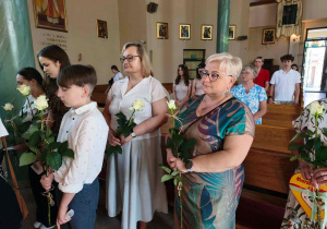 Uczniowie i nauczyciele z symbolicznymi białymi różami