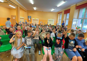 Widownia - dzieci z wszystkich grup siedzą rzędami, w tle widok na szkolną jadalnię