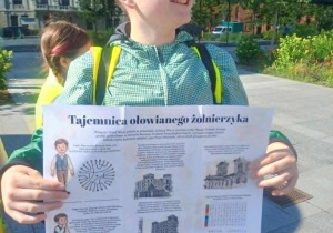 Chłopiec trzyma wydruk z "Historią zaginionego żołnierzyka"
