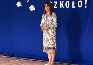 Pani Dyrektor na tle niebiskiej dekoracji z napisem witaj szkoło