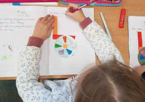 Dziecko przykleja kolorowe paski do zeszytu