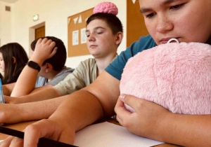 Uczniowie z atrybutami zajęć - mózgiem maskotką pracują nad testem