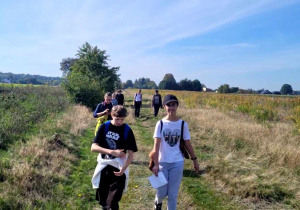 Wędrówka uczniów polnymi drogami - zielono brązowe pola i błękitne niebo nad nimi