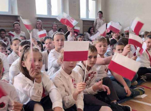Dzieci w strojach galowych z flagami Polski