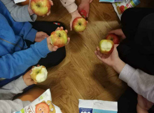 Dzieci trzymają w dłoniach jabłka
